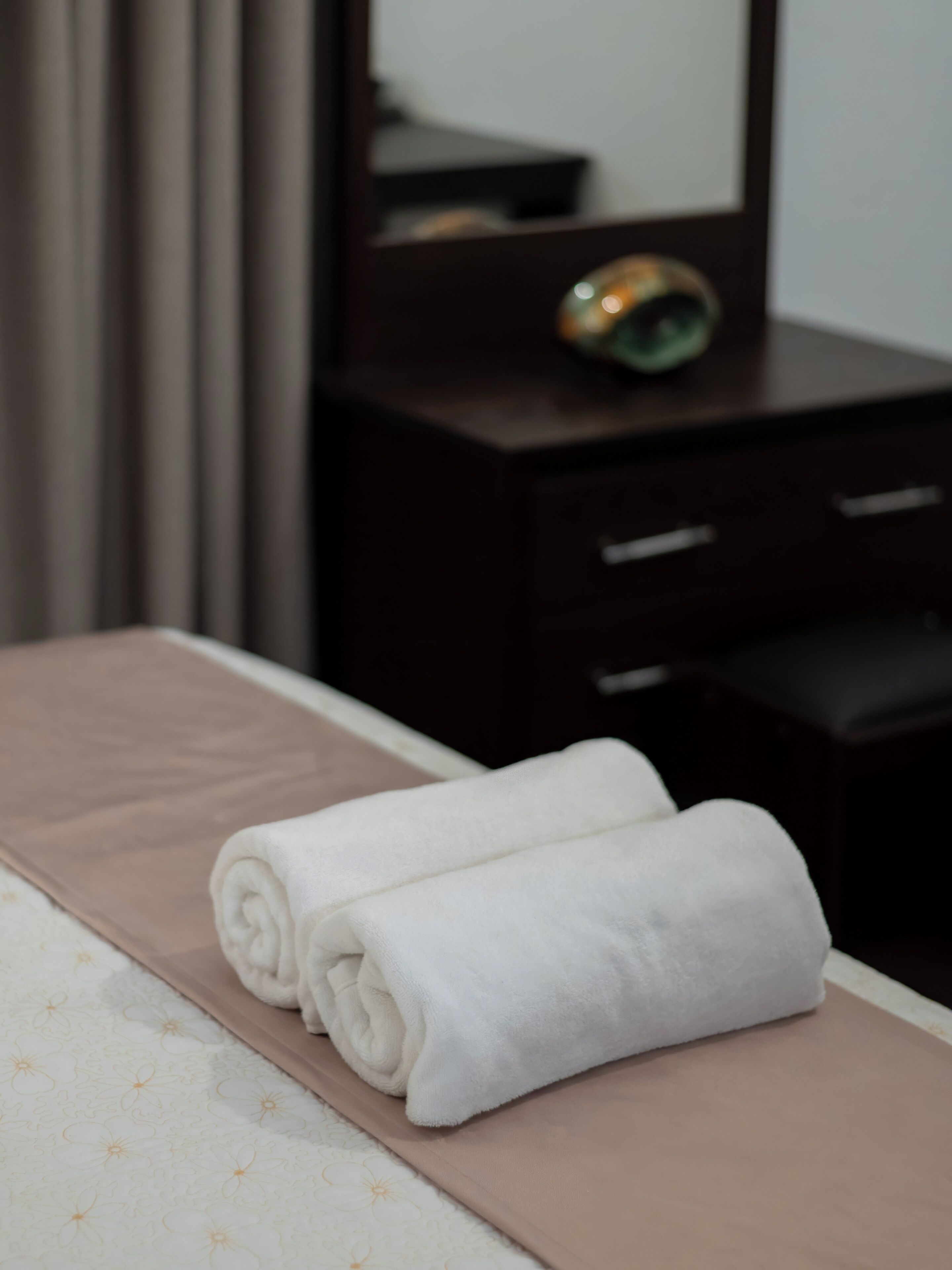 A neatly made bed with a white towel and a brown bedspread.