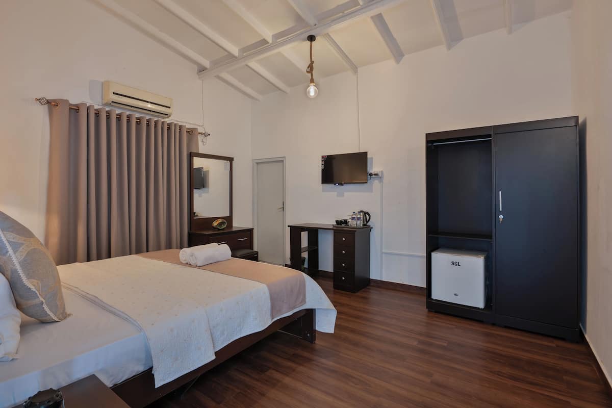 Une chambre à coucher comprenant un lit, une armoire, un bureau, un téléviseur et un appareil de climatisation.
