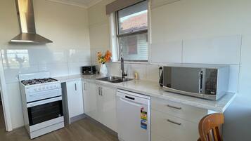 A modern kitchen with white cabinetry, a gas stove, a microwave, and a dishwasher.