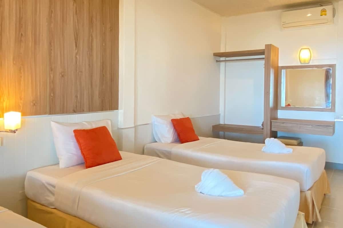 Quarto de hotel com duas camas, parede de madeira, luminária no teto, ar condicionado e um espelho.