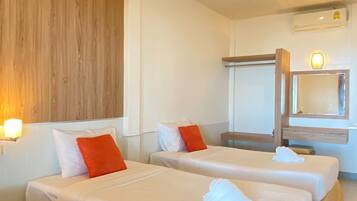 Habitación de hotel con dos camas, pared de madera, una lámpara en el techo, un equipo de aire acondicionado y un espejo.