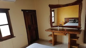 A bedroom with a bed, wooden dresser, and a mirror.