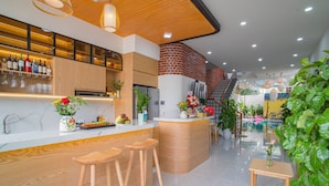A modern kitchen with wooden bar stools, a white countertop, and a brick wall. - Mint Hoi An Villa (Da Nang)