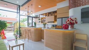 A modern kitchen with wooden cabinets, a bar area, and a reception desk. - Mint Hoi An Villa (Da Nang)