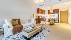 A modern living room with a sofa, coffee table, and dining area. - Manzil - 1BR | Near La Mer Beach | Pool & Sea View (Dubai)
