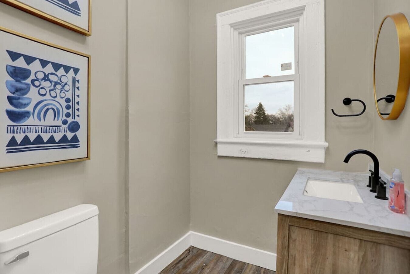 A bathroom with a window, a sink, and a toilet.