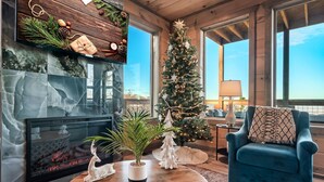 A cozy living room with a fireplace, a Christmas tree, and a blue armchair.