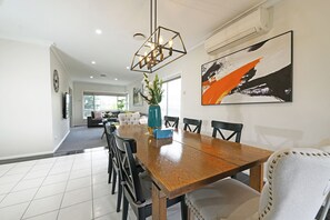 Un comedor moderno con una mesa de madera, sillas negras y un jarrón con flores.