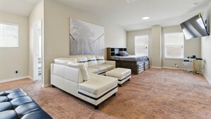 A spacious bedroom with a large sectional sofa, a bed, a desk, and a mounted TV. - Gorgeous 5-bedroom home in Schertz, San Antonio, New Braunfels (Schertz)