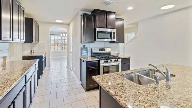 A modern kitchen with granite countertops, stainless steel appliances, and dark cabinetry. - Gorgeous 5-bedroom home in Schertz, San Antonio, New Braunfels (Schertz)