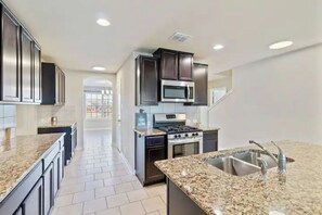 A modern kitchen with granite countertops, stainless steel appliances, and dark cabinetry.