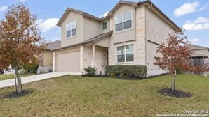 A two-story house with a garage, a front lawn, and mature trees. - Gorgeous 5-bedroom home in Schertz, San Antonio, New Braunfels (Schertz)