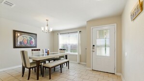 A dining area with a table, chairs, a bench, a chandelier, a window with blinds, and a door with a glass panel. - Gorgeous 5-bedroom home in Schertz, San Antonio, New Braunfels (Schertz)
