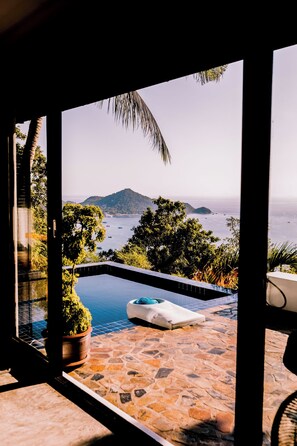 A view from a room with a stone patio and a pool, overlooking a body of water and distant islands. - Lunar Villas Koh Tao - Luxury Pool Villa (Koh Tao)
