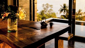 A wooden table with a vase of flowers and a teapot, overlooking a scenic view. - Lunar Villas Koh Tao - Luxury Pool Villa (Koh Tao)