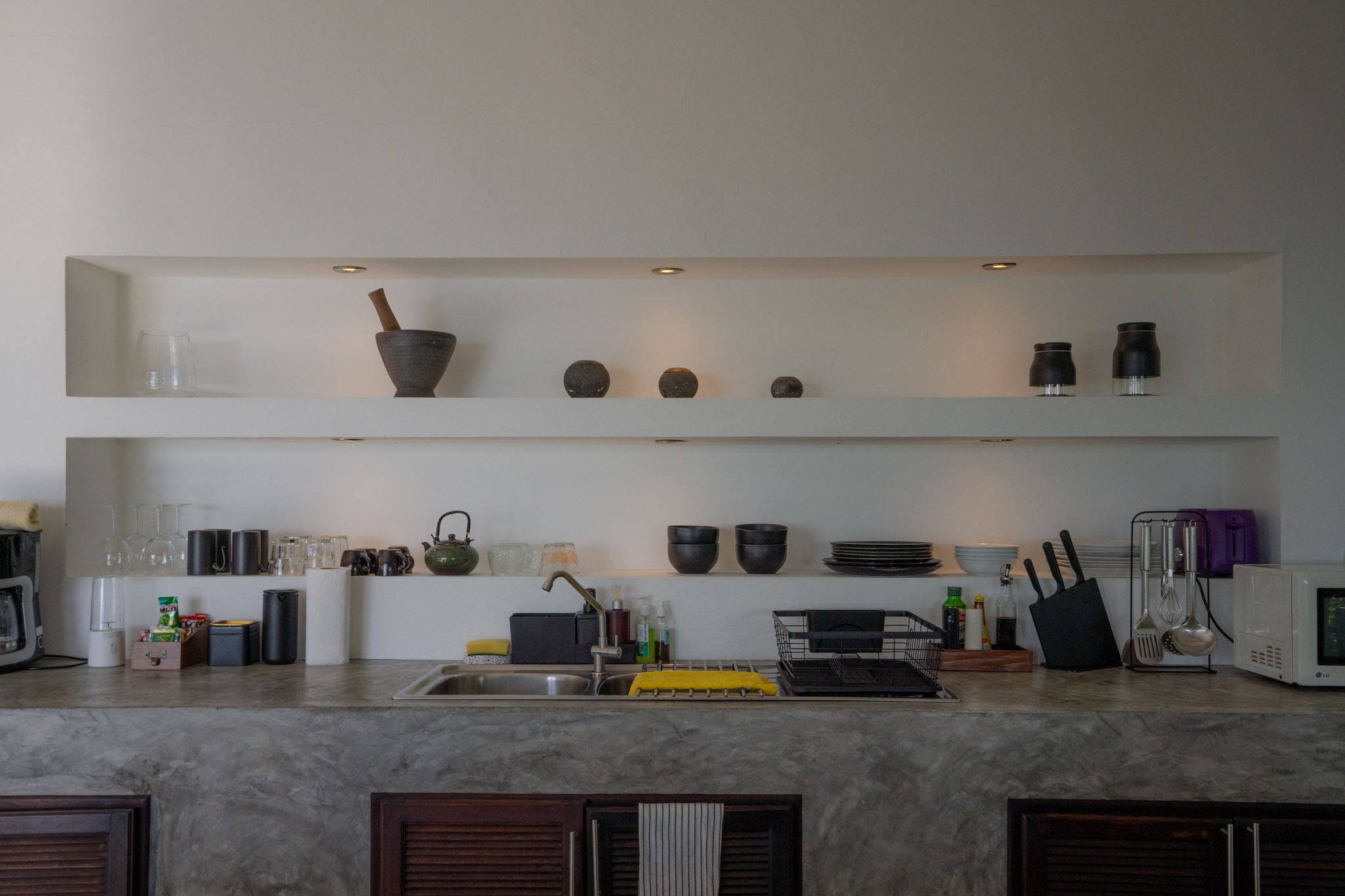 Una cocina moderna con estantes blancos, un lavamanos y diversos utensilios de cocina.