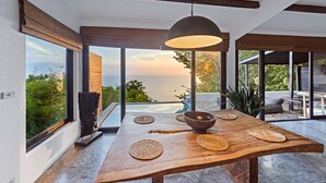 A modern dining area with a wooden table, woven placemats, and a large bowl. - Lunar Villas Koh Tao - Luxury Pool Villa (Koh Tao)