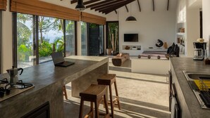 A modern kitchen with a large island, pendant lighting, and a view of the outdoors. - Lunar Villas Koh Tao - Luxury Pool Villa (Koh Tao)