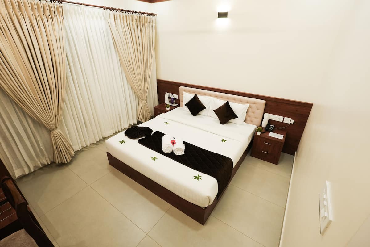 A neatly made double bed with a wooden headboard, a bedside table with a lamp, and a curtain on the window.