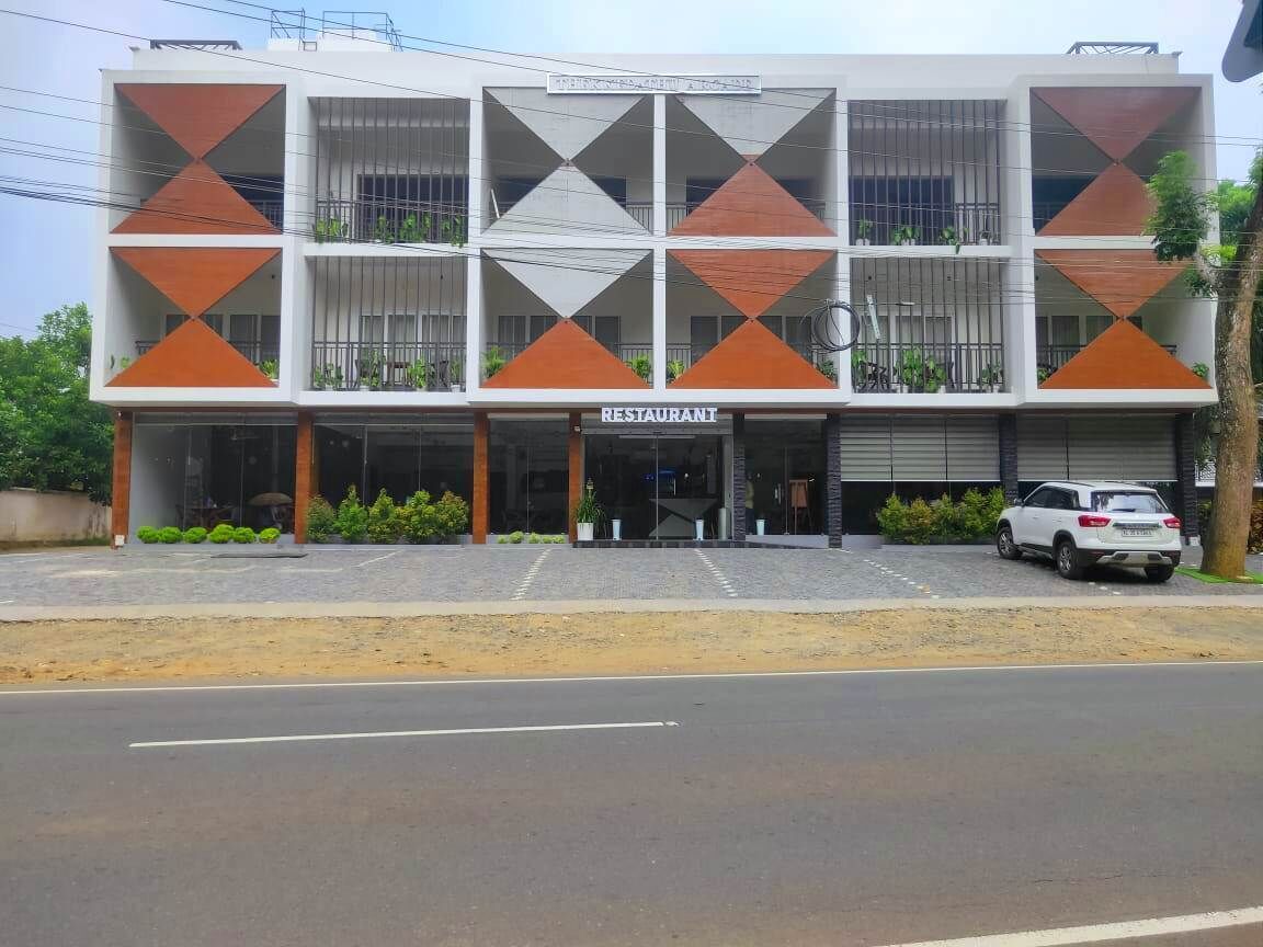 Un edificio moderno con un restaurante en la planta baja. Presenta una fachada geométrica con paneles alternados en blanco y naranja.