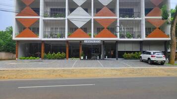 Un edificio moderno con un restaurante en la planta baja. Presenta una fachada geométrica con paneles alternados en blanco y naranja.