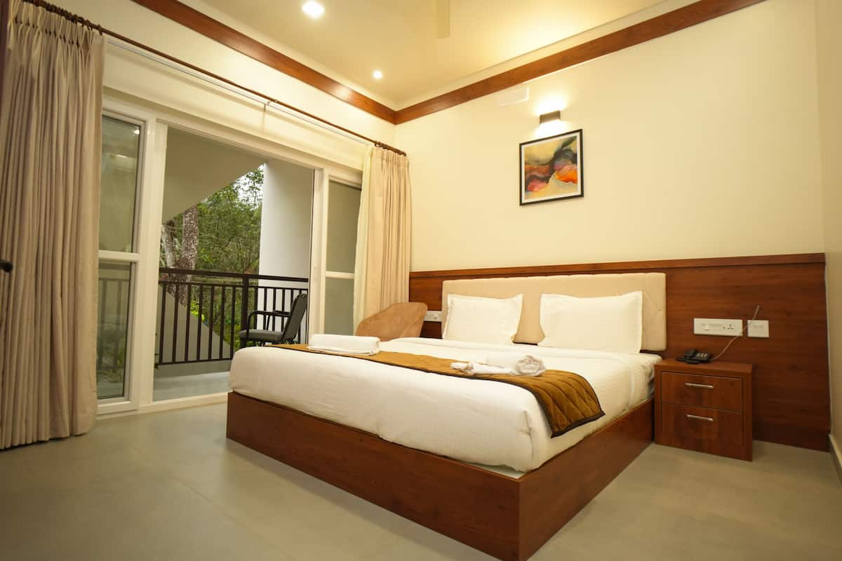 A hotel room with a large bed, a wooden headboard, a nightstand, and a view of the outdoors through a sliding glass door.