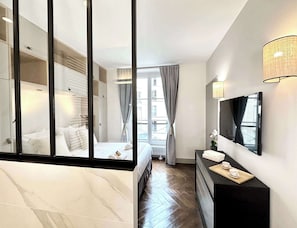 Une chambre d’hôtel moderne équipée d’un lit, d’une commode, d’un miroir et d’une fenêtre avec des rideaux.