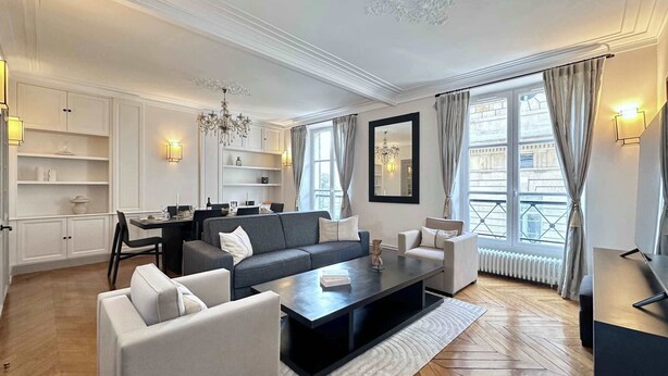 A modern living room with a sofa, coffee table, and dining area.