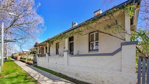 Une rangée de maisons blanches, avec un étroit trottoir et une clôture en bois.
