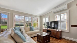 Un salon avec un canapé d’angle beige, une table basse en bois et un téléviseur à écran plat.