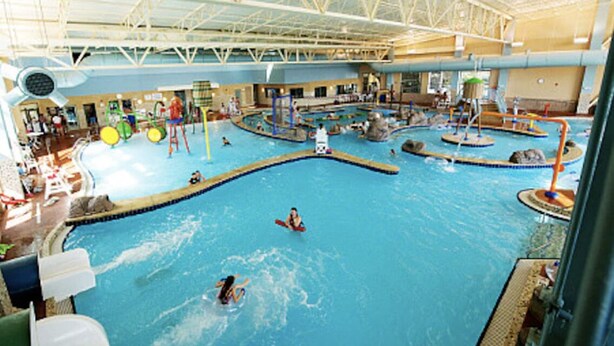 Ein Hallenbad mit mehreren Bahnen, Wasserrutschen und Spielbereichen.