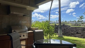 Une cuisine équipée d’un barbecue, un coin repas avec des chaises et une vue sur un paysage volcanique.