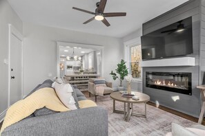Un salon moderne avec une cheminée, un canapé, une table basse et un coin repas.