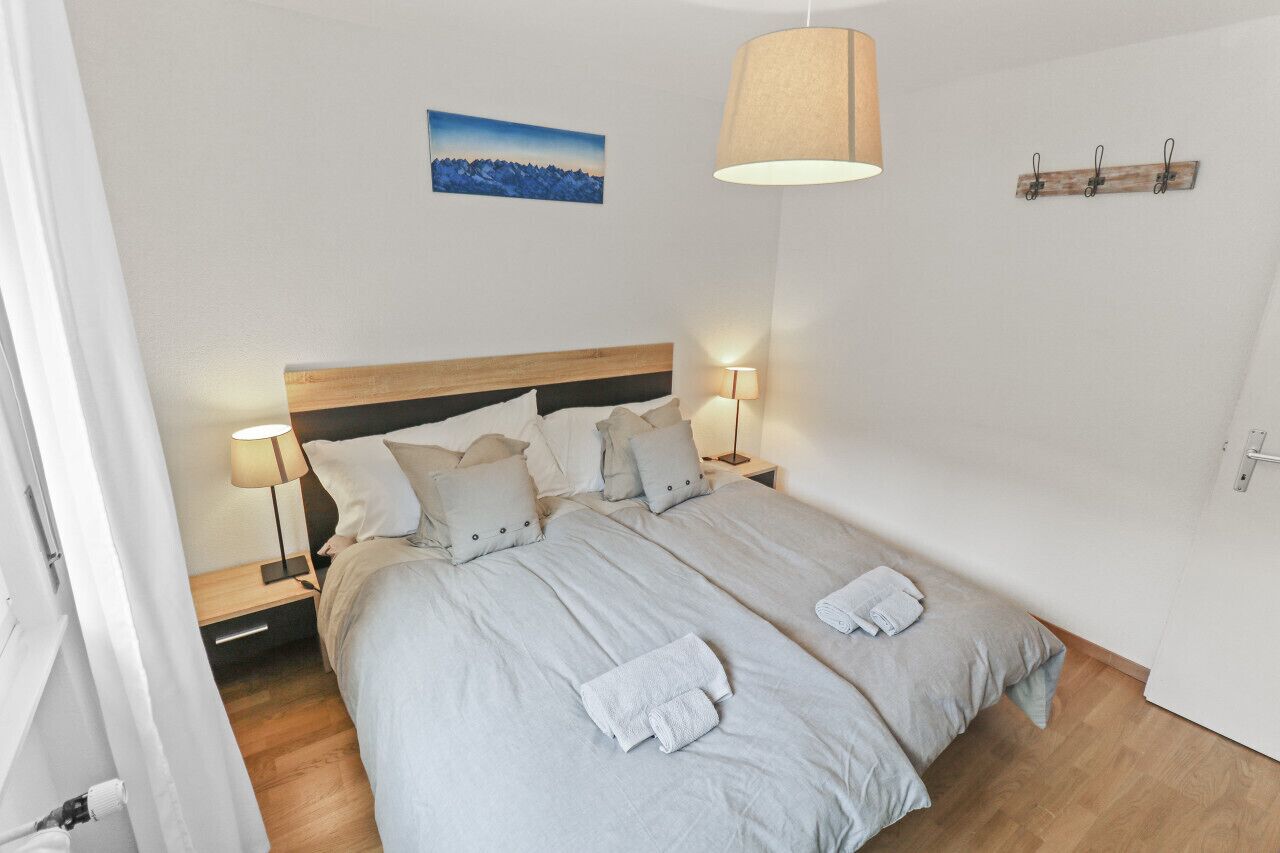 Una cama doble con dos mesitas de noche, cada una con una lámpara, un cabecero de madera y un cuadro en la pared.