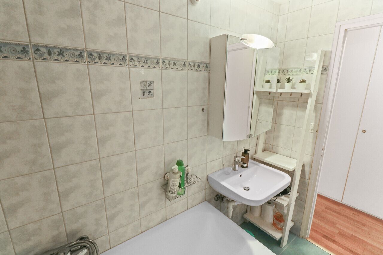 Ein Badezimmer mit weißem Waschbecken, Spiegel und gefliesten Wänden.