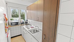 Una cocina moderna con armarios blancos, microondas, cafetera y pileta.