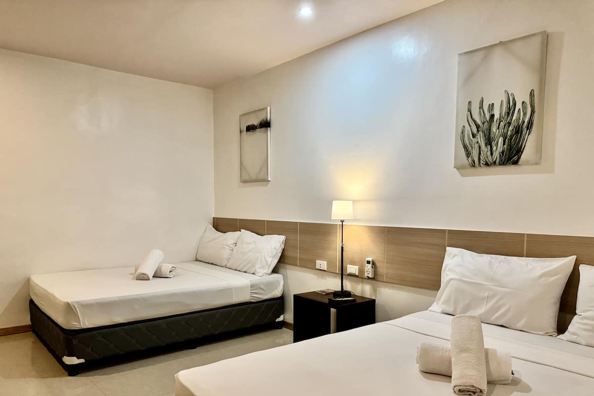 Una habitación de hotel con dos camas, una mesita de noche, una lámpara y una obra de arte colgada en la pared.