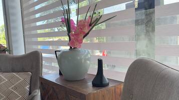 A modern living room with a sofa, a coffee table, and a vase with pink flowers.