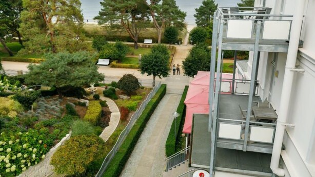 A hotel with a balcony overlooking a landscaped garden and the sea. - App.6 Zinnowitzer Hof by Interhome (Zinnowitz)