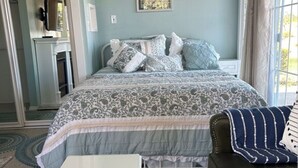 Un dormitorio con una cama, una mesa blanca, un sofá de cuero y una alfombra estampada.