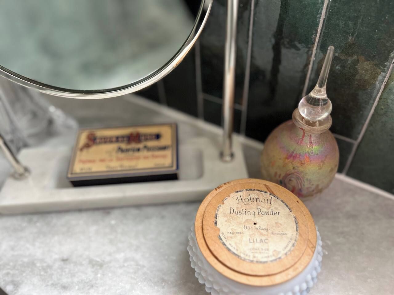 Ein hölzerner Behälter mit dem Aufdruck 'Hobnail Dusting Powder' auf einer Badezimmerablage.