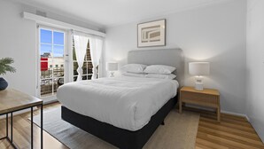 Een moderne slaapkamer met een groot bed, een nachtkastje met een lamp en uitzicht door een schuifdeur.