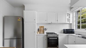 Een moderne keuken met witte kasten, een roestvrijstalen koelkast, een gasfornuis en een magnetron.