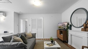 Een moderne woonkamer met een grijze bank, een witte salontafel en een grote spiegel.