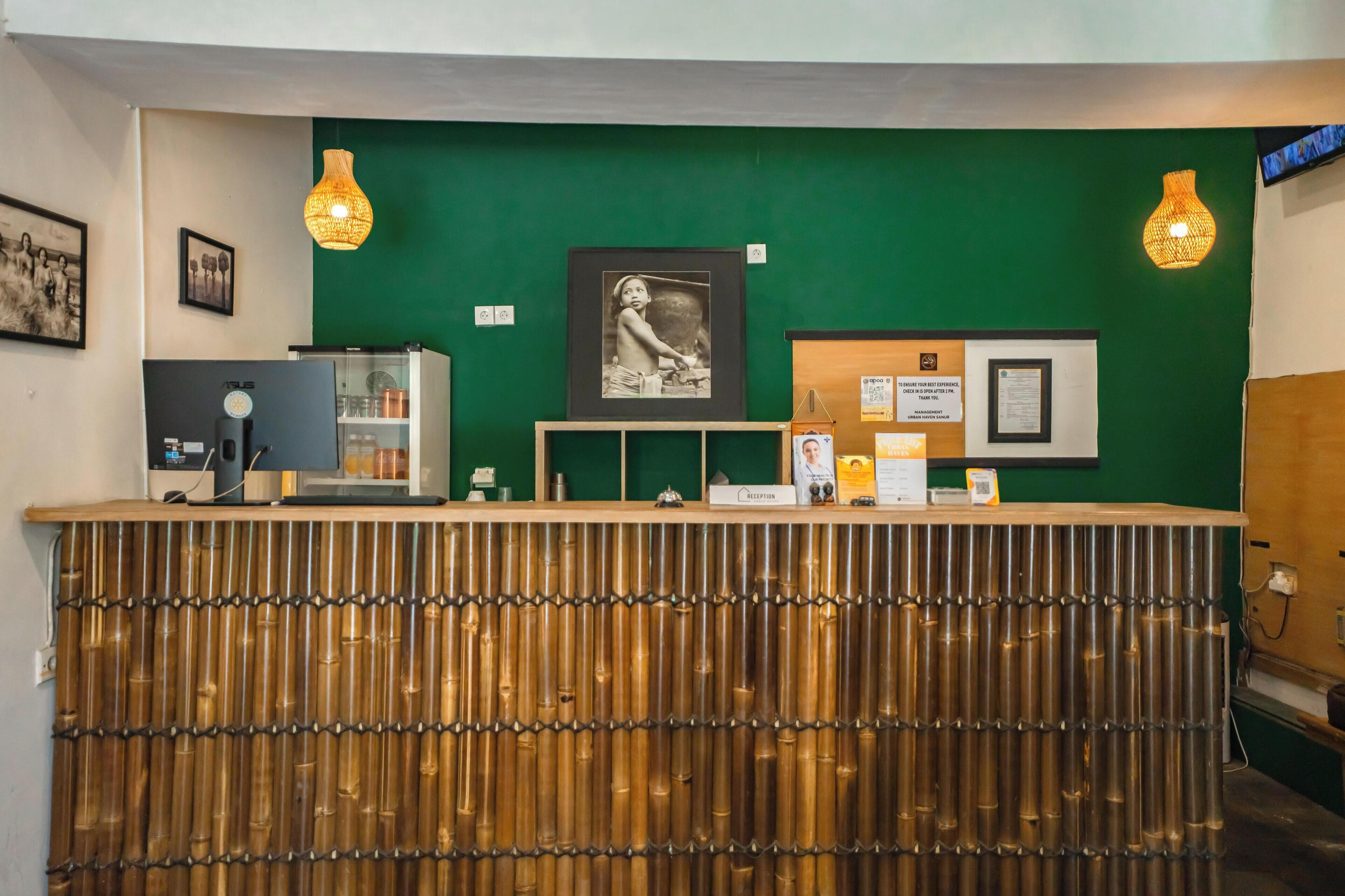 Una recepción con una pared verde, cuadros enmarcados y un reloj.