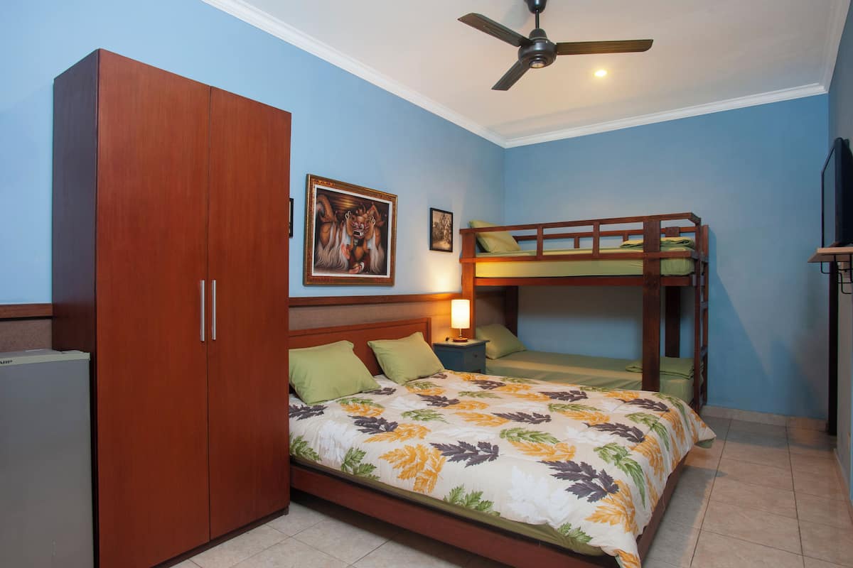 A bedroom with a bunk bed, a wardrobe, a ceiling fan, and a bed with floral bedding.
