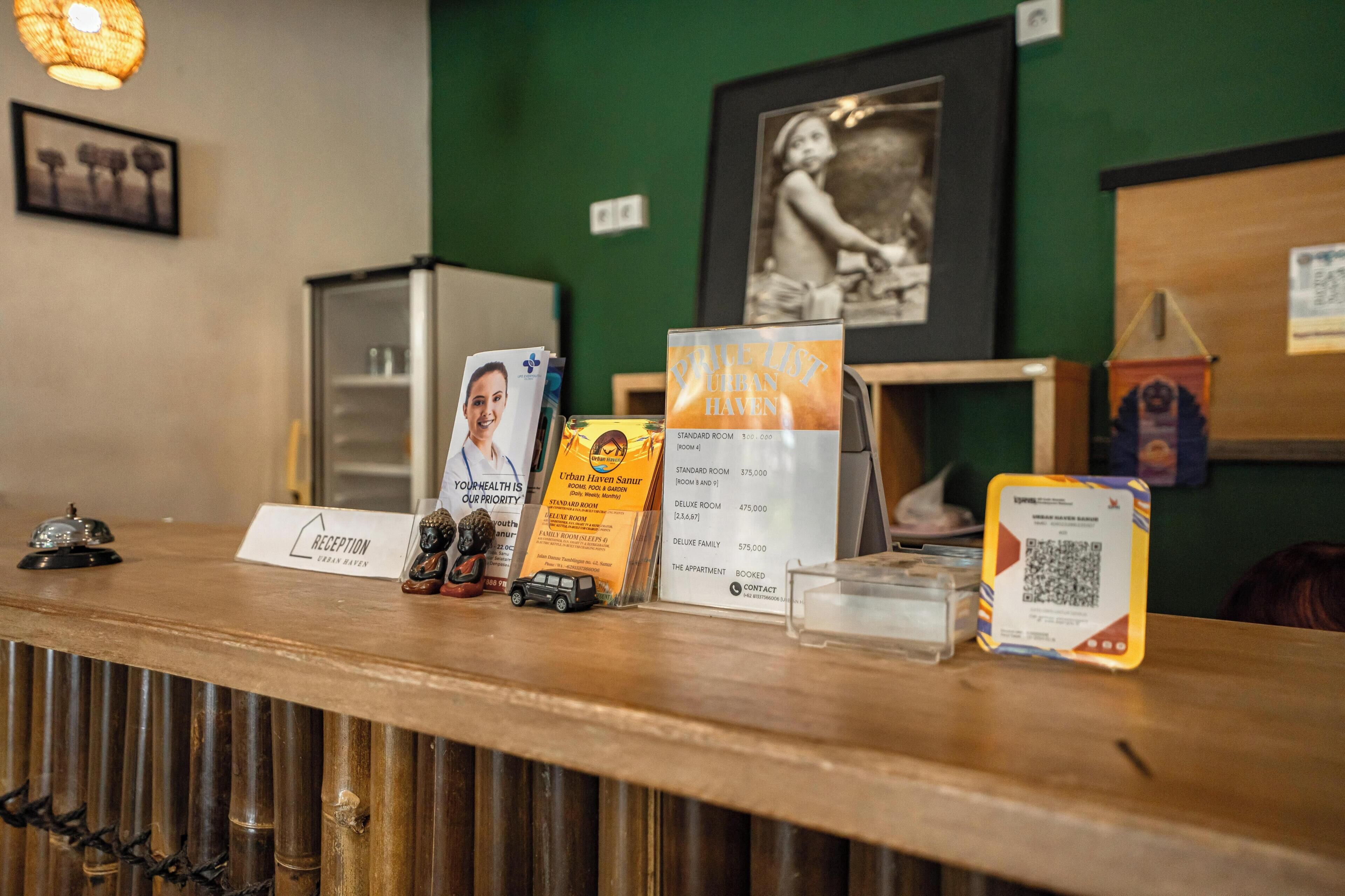 A reception desk with a sign for Urban Haven, a framed picture on the wall, and a QR code on the counter.