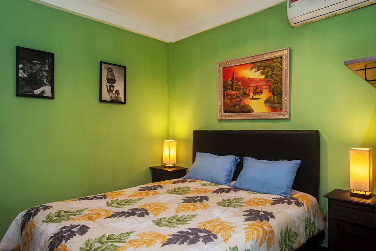A room with a bed, two nightstands, and a wall with three framed pictures.