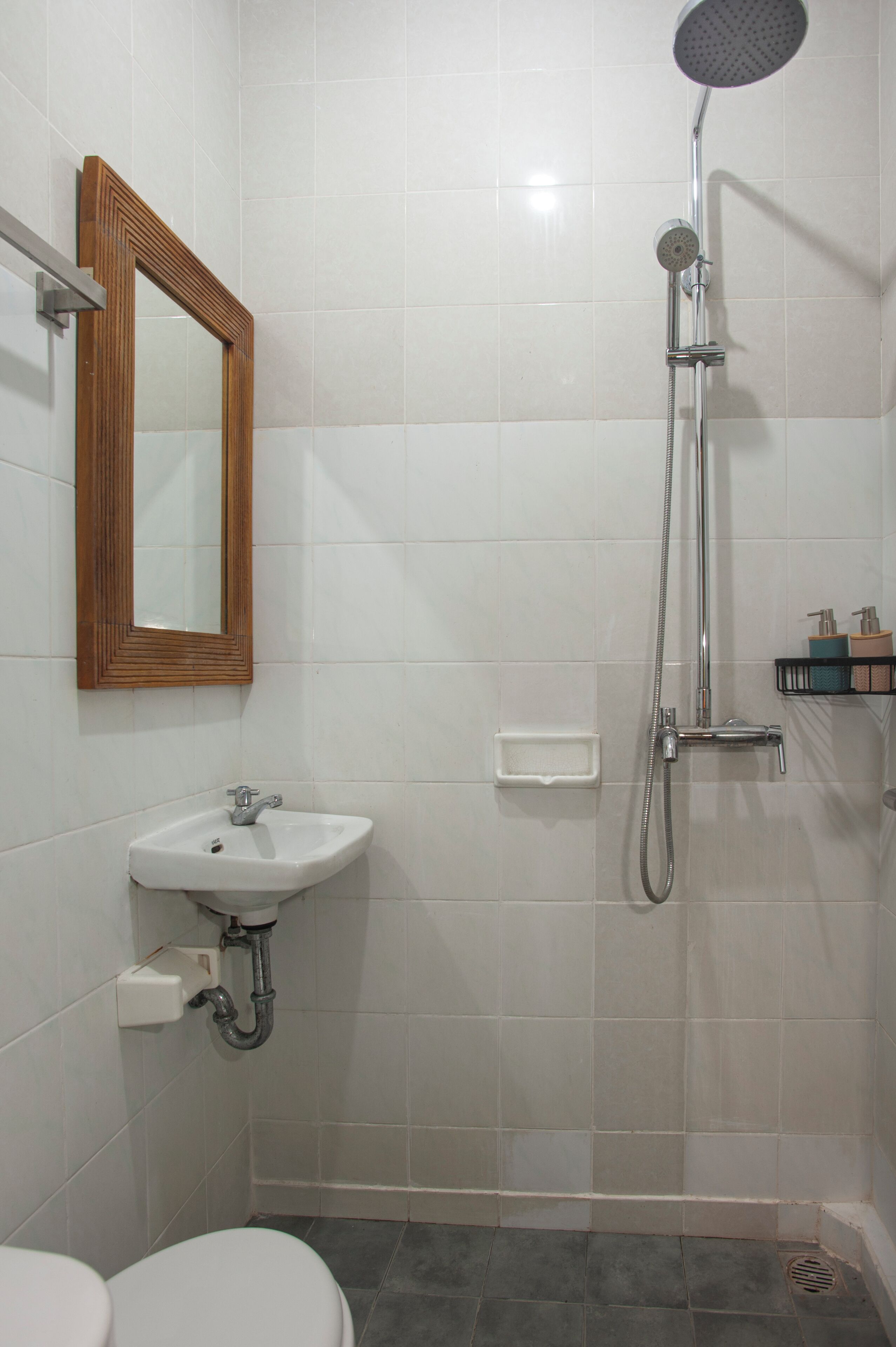 A bathroom with a shower, sink, toilet, and a mirror.