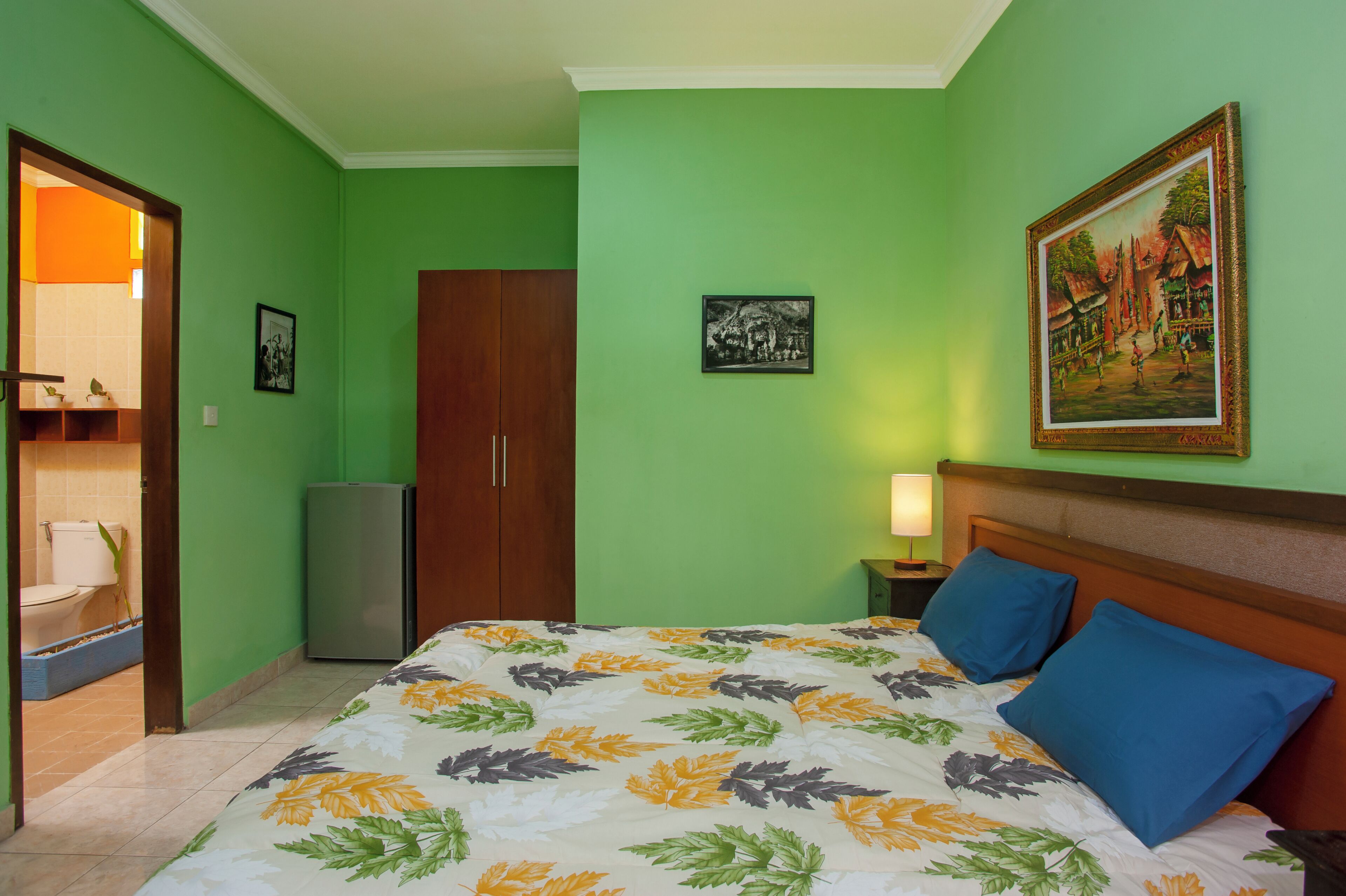 Ein Hotelzimmer mit Bett, Schrank, kleinem Kühlschrank, Toilette und Waschbecken.